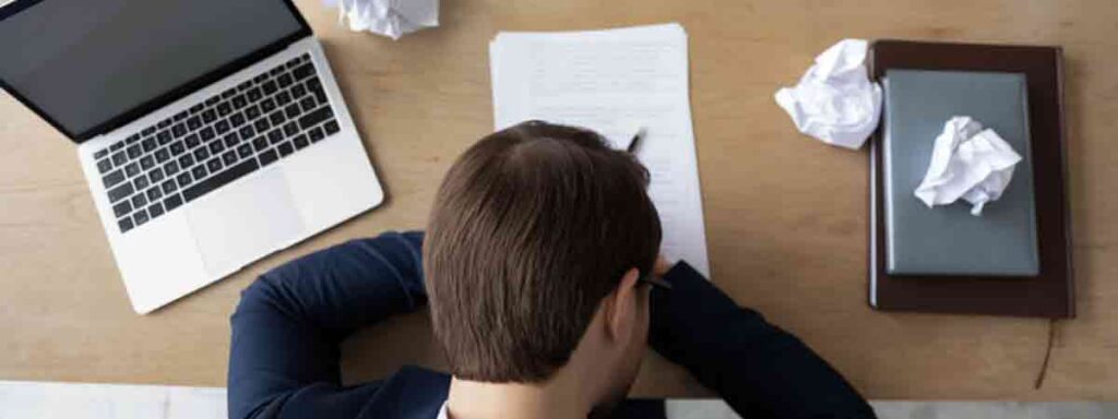 image shows frustrated employee at his desk